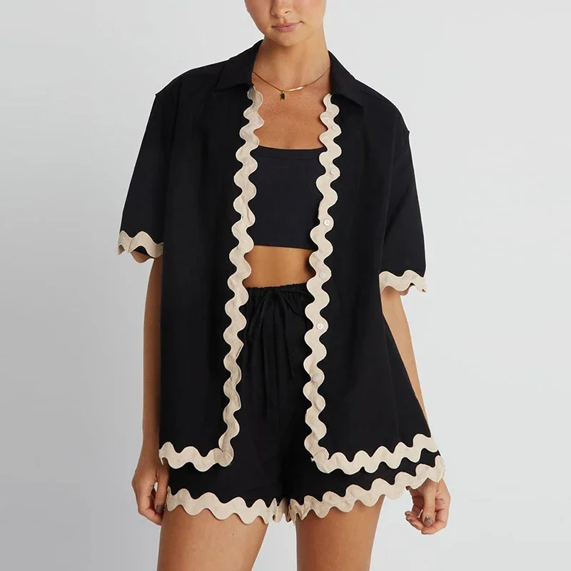 Black outfit with white ruffle details on a plain background