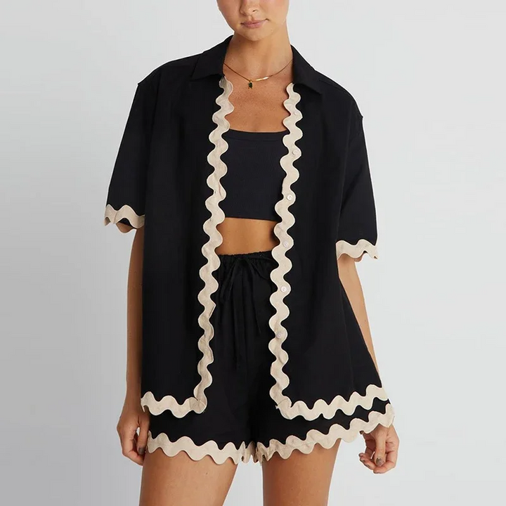 Black outfit with white ruffle details on a plain background