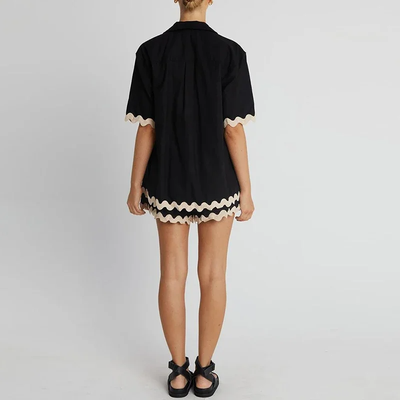 Person wearing a black outfit with white trim on a plain background