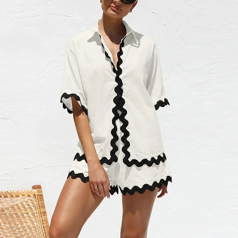 Woman wearing a white cover-up with black trim against a white background