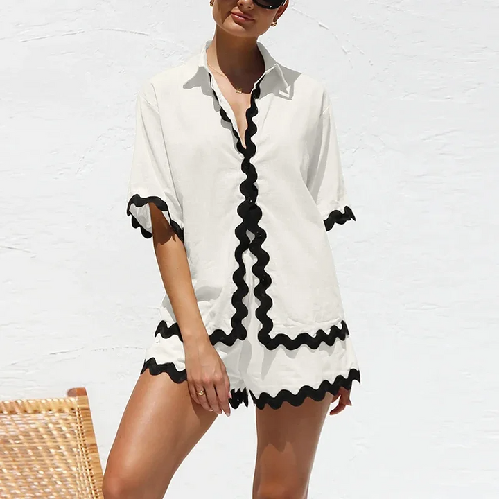 Woman wearing a white cover-up with black trim against a white background