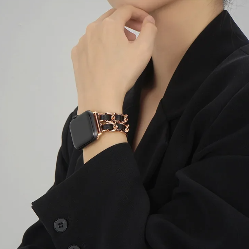 Person wearing a black smartwatch with a rose gold band on a plain background