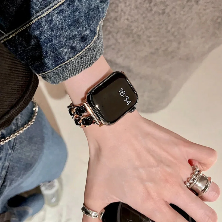 Smartwatch on a wrist with a person wearing jeans and multiple rings.