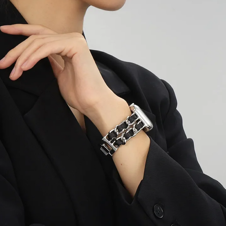 Person wearing a black and silver bracelet on a plain background