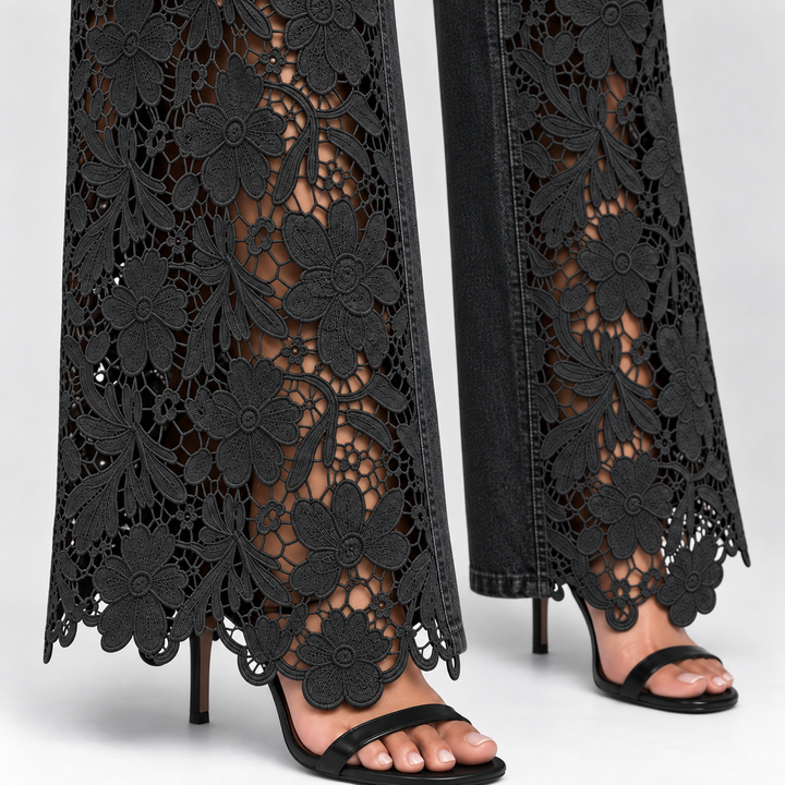 Black wide-leg jeans with an intricate floral lace overlay and cutout pattern, shown on a model wearing black heeled sandals against a light gray background.