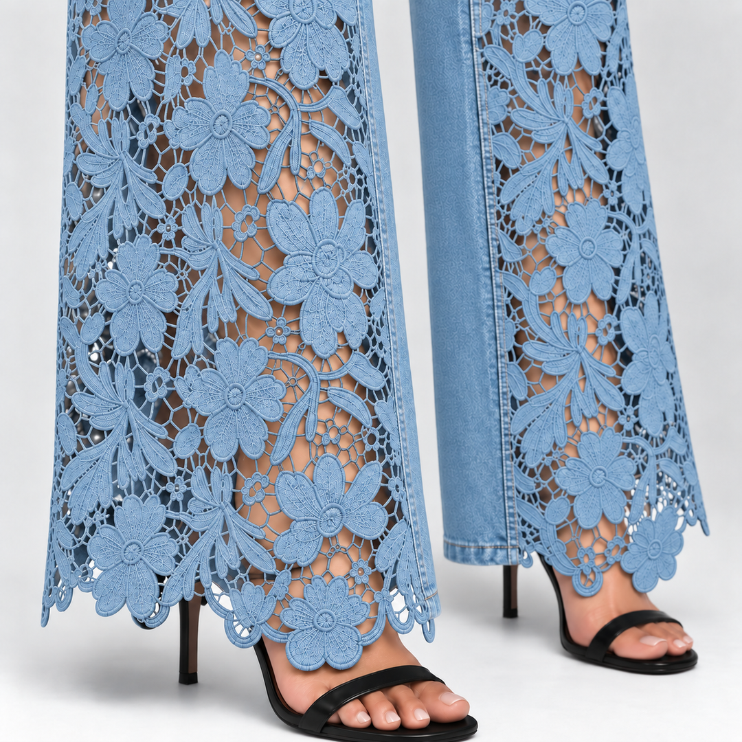 Close-up of a person wearing light blue wide-leg lace-up jeans with floral cutout embroidery and black heeled sandals against a light gray studio background.