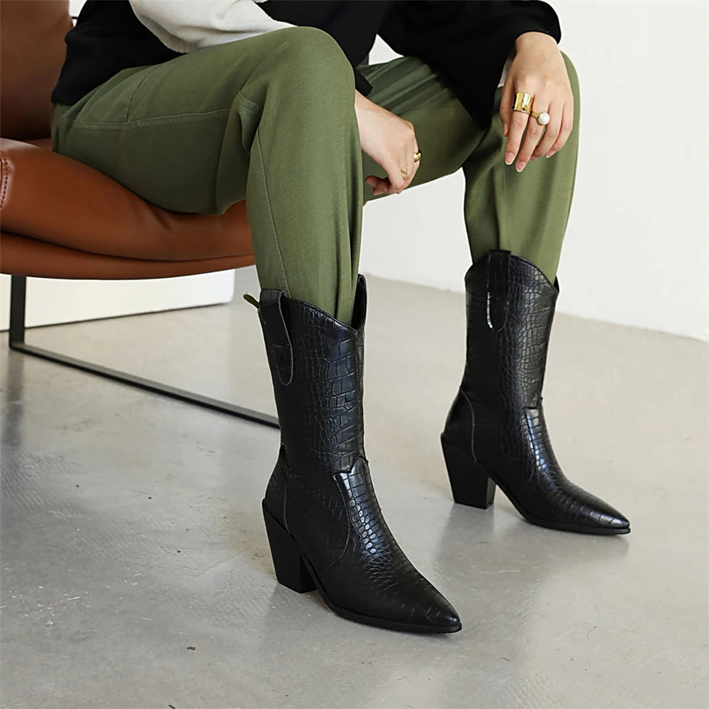 Person wearing black knee-high boots with a textured pattern, sitting on a brown chair.