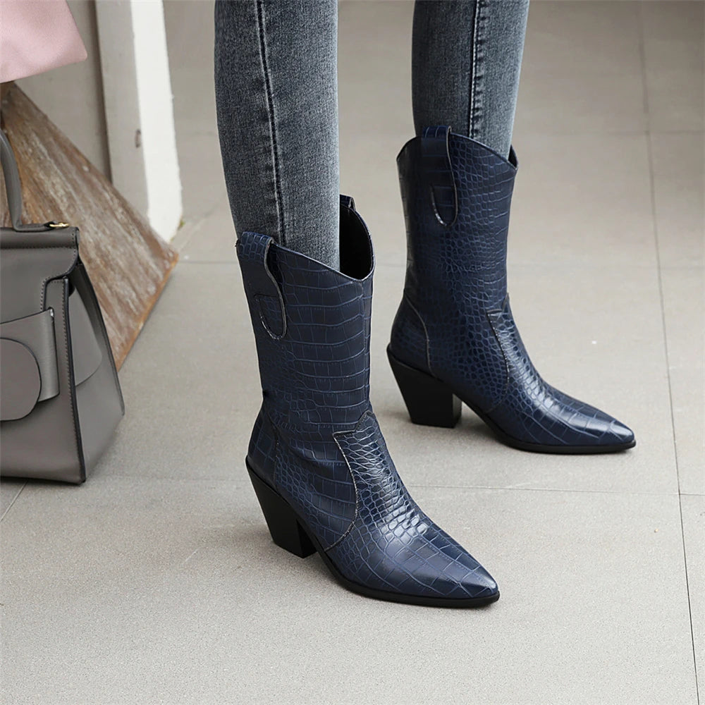 Blue crocodile-patterned boots worn with gray jeans on a light gray floor.