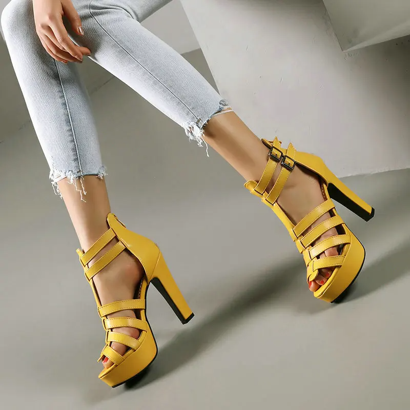 Yellow high-heeled sandals worn with light blue jeans on a neutral background