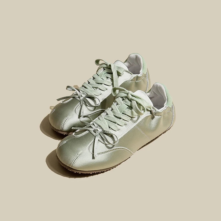 Pair of light green sneakers on a beige background