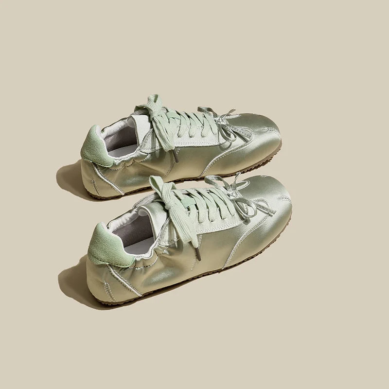 Pair of light green sneakers on a beige background