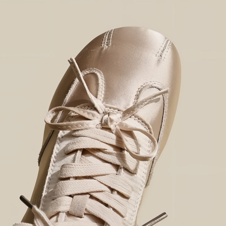 Close-up of a beige sneaker with laces on a beige background