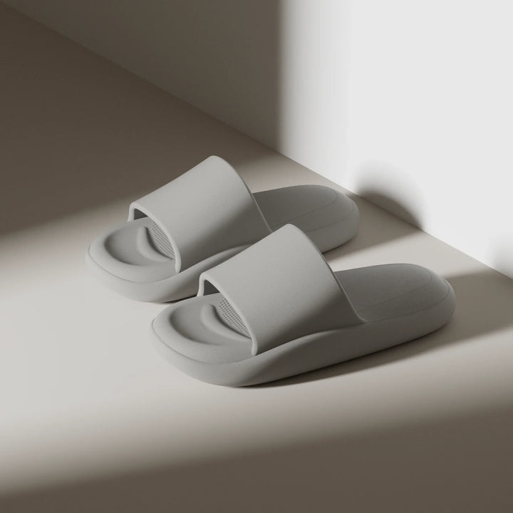Pair of gray slippers on a light surface with a soft shadow