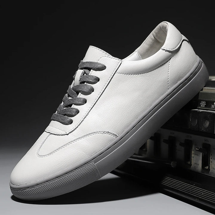 White leather sneaker with gray laces on a dark background