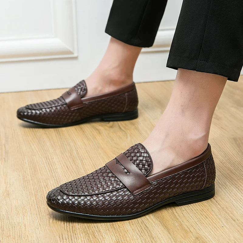 Brown woven loafers worn indoors on a wooden floor.