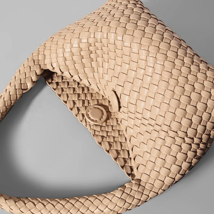 Close-up of a woven beige handbag on a gray background