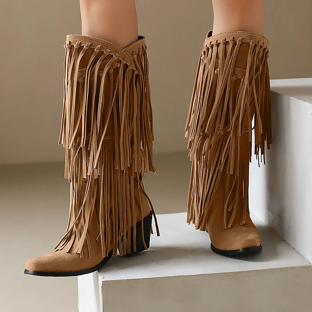 Tan fringe boots on a white surface with a neutral background