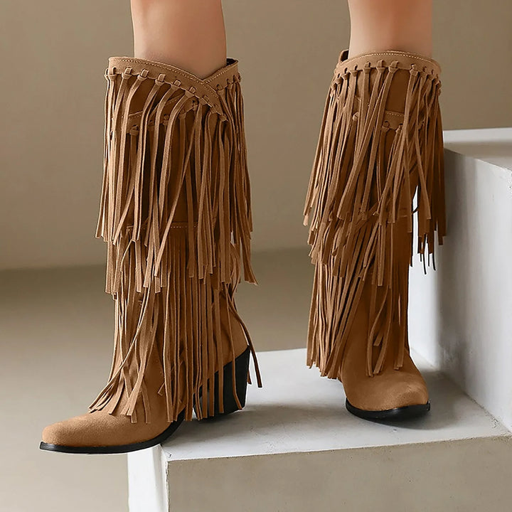 Tan fringe boots on a white surface with a neutral background