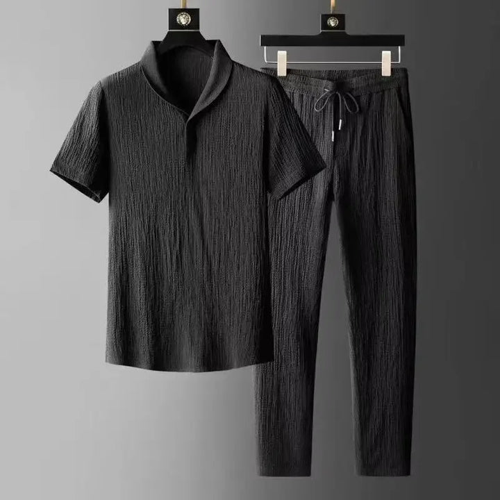 Black textured shirt and pants set on hangers against a gray background