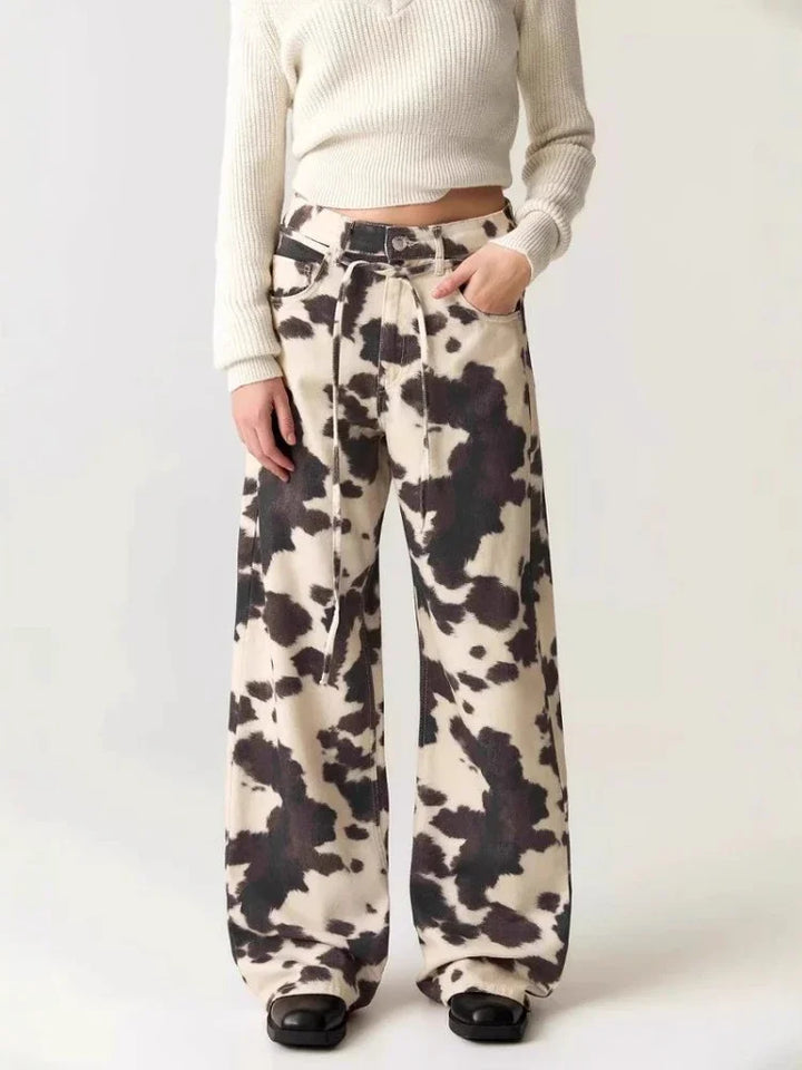 Person wearing cow print pants on a white background