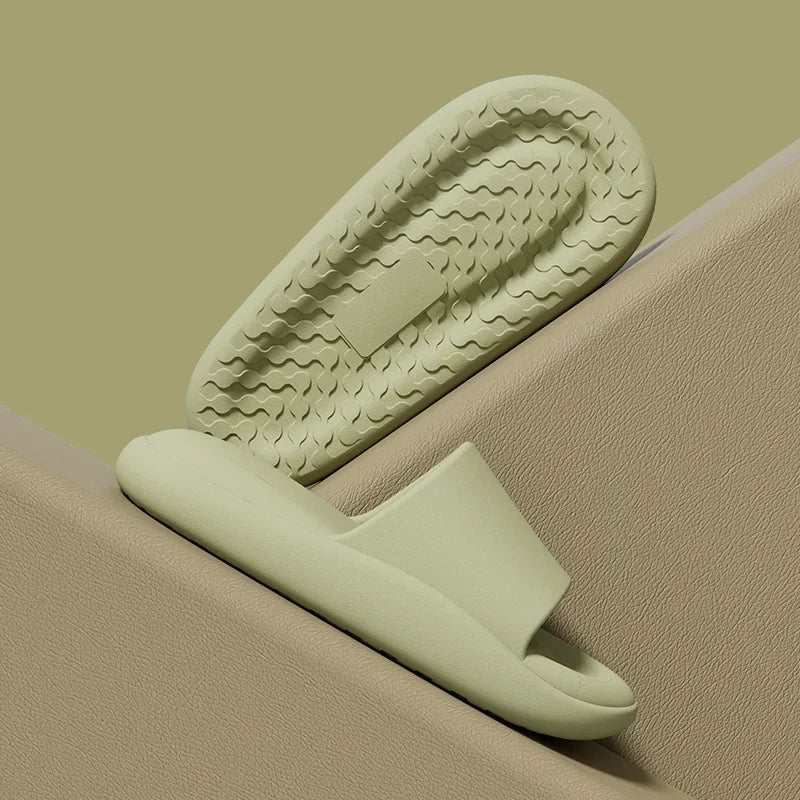 Light green slide sandal on a beige surface with a green background