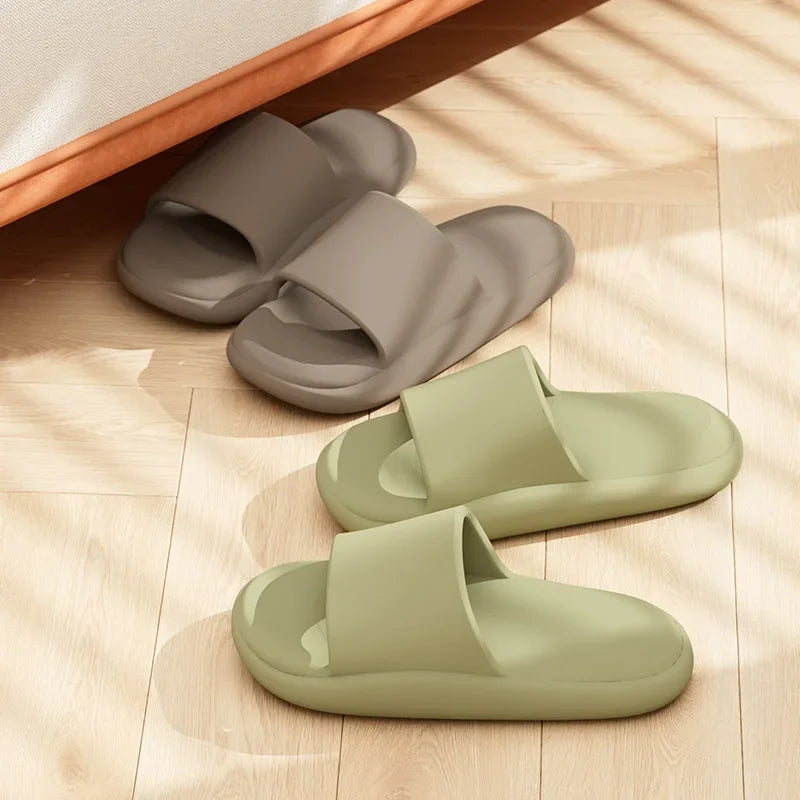 Two pairs of slides, one gray and one green, on a wooden floor.
