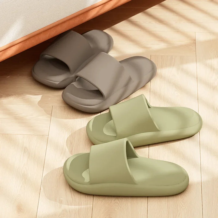 Two pairs of slides, one gray and one green, on a wooden floor.