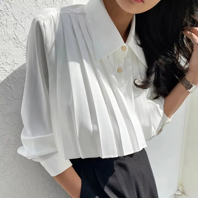 Person wearing a white blouse with a neutral background