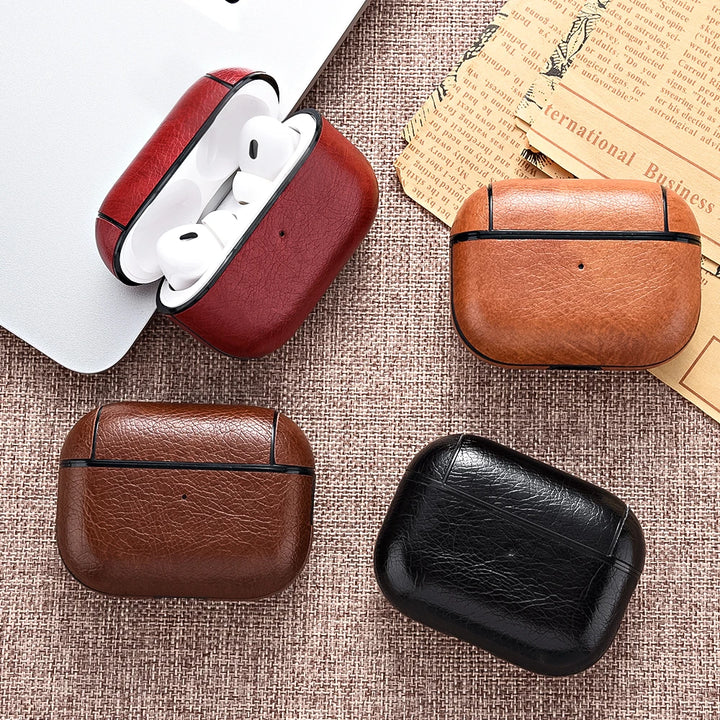 Four leather cases for wireless earbuds in red, brown, and black on a textured surface.