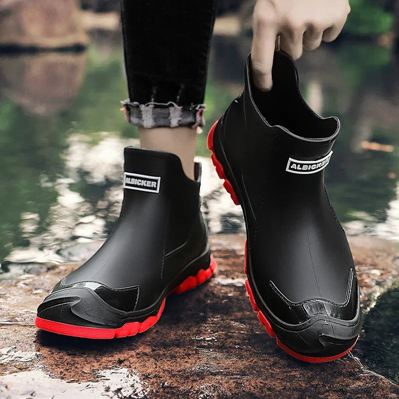 Black rain boots with red soles held by a person near water