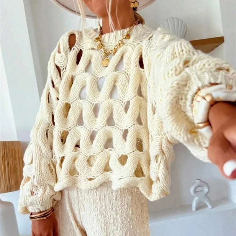Person wearing a cream-colored knitted sweater with a white background