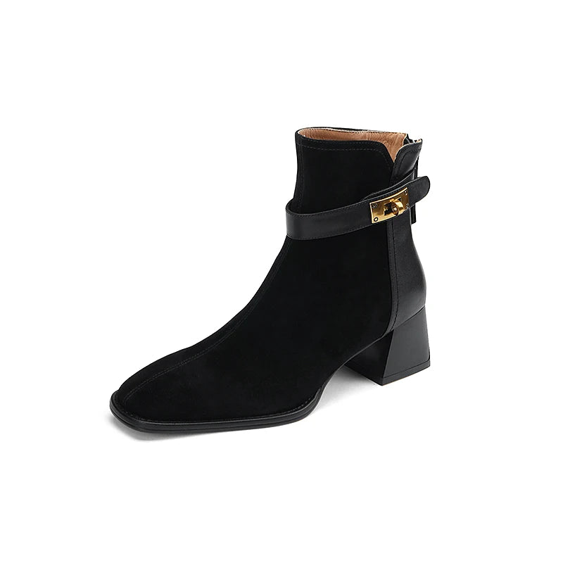 Black ankle boot with gold buckle on a white background