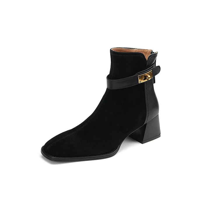 Black ankle boot with gold buckle on a white background