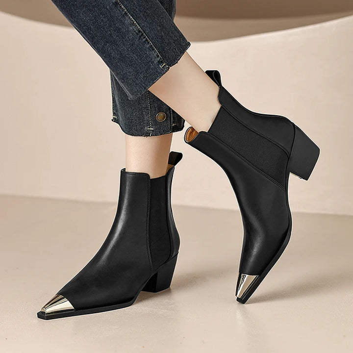Black ankle boots with metallic heel on a neutral background