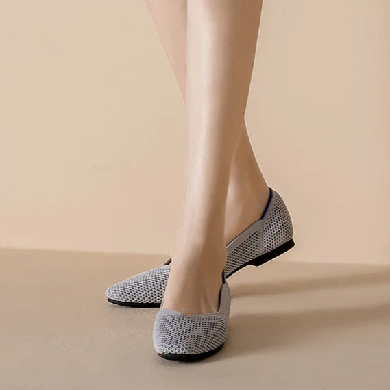 Gray flat shoes worn with a white skirt on a beige background, featuring an online store text overlay.