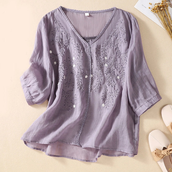 Purple blouse with floral embroidery on a beige background