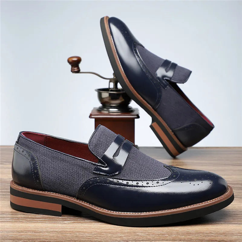 Navy blue leather loafers with brown soles on a wooden surface.