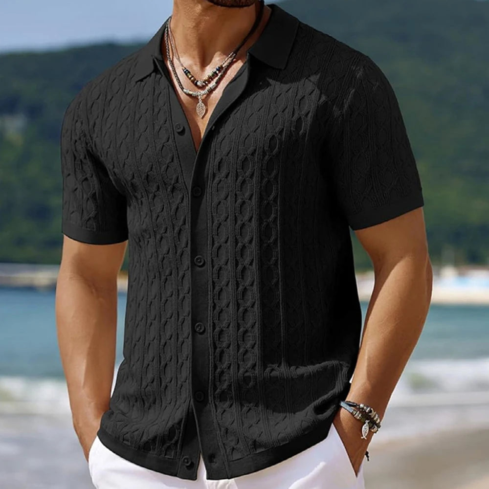 Man wearing a black textured shirt with a blurred beach background
