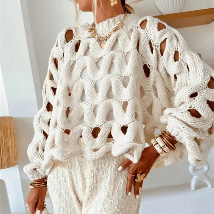 Person wearing a white knit sweater with cut-out design in an indoor setting