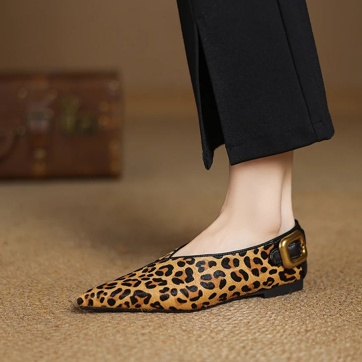 Leopard print flat shoe with a gold buckle on a neutral background