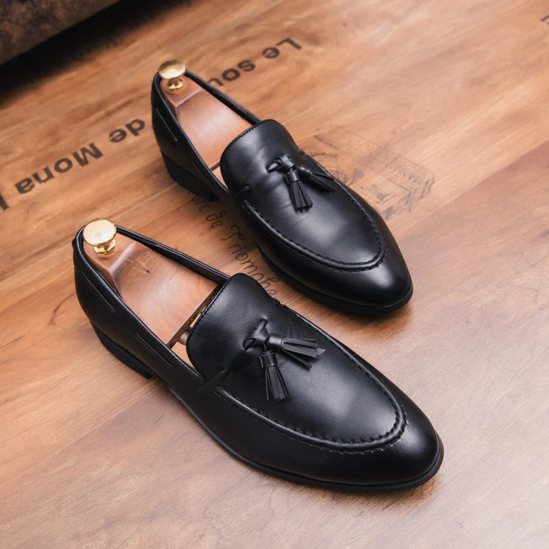 Black loafers with tassels on a wooden surface