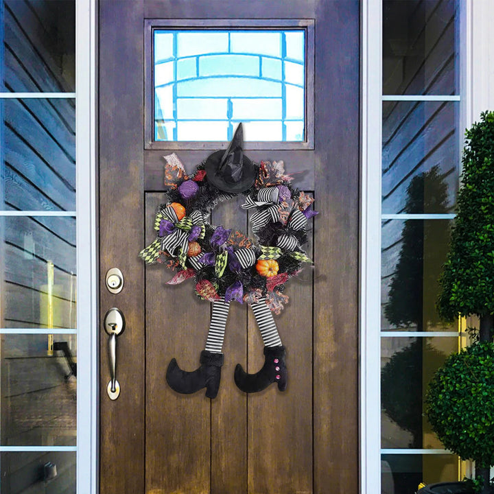 Halloween wreath with witch hat, boots, and colorful accents on a wooden door.