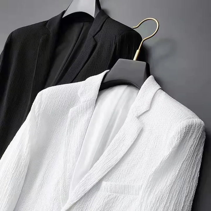 Black and white blazers on hangers against a gray background