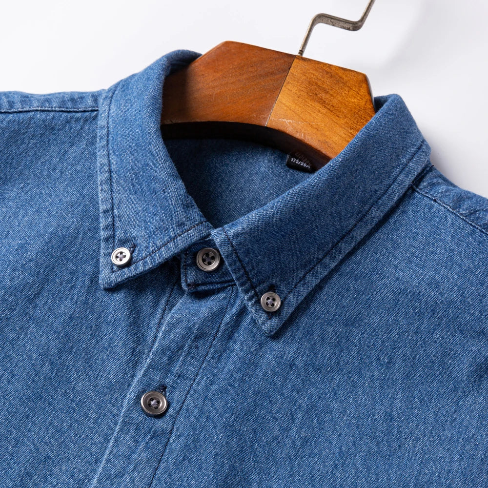 Blue denim shirt on a wooden hanger against a white background