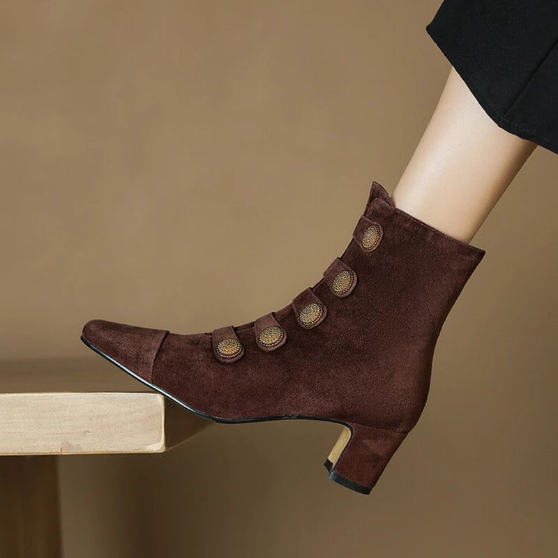 Brown suede ankle boots with gold buttons on a brown background