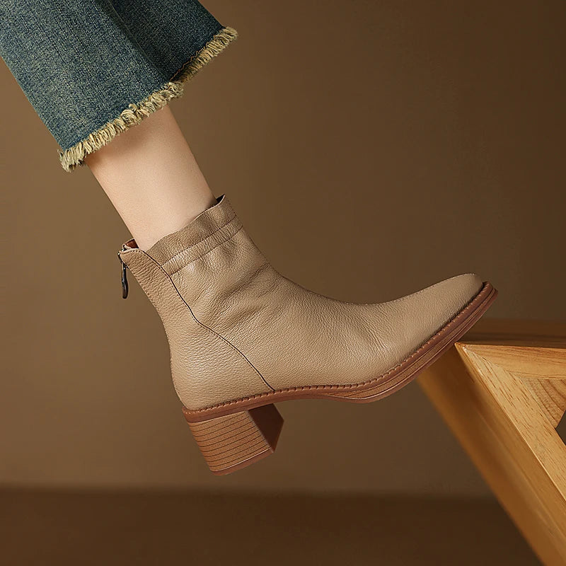Beige ankle boot worn with a casual outfit on a brown background