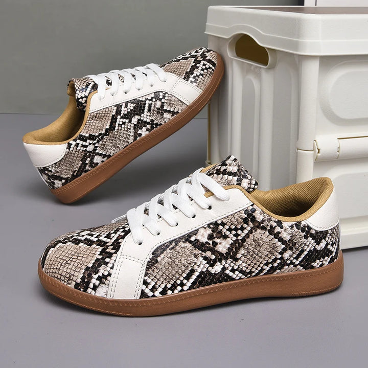 Pair of snakeskin-patterned sneakers with white accents on a gray surface.