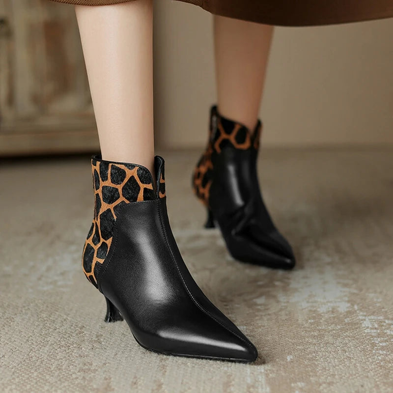 Black ankle boots with leopard print details on a neutral background
