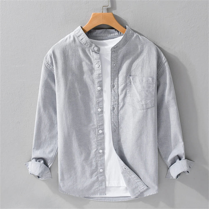 Light gray button-up shirt on a wooden hanger against a gray background