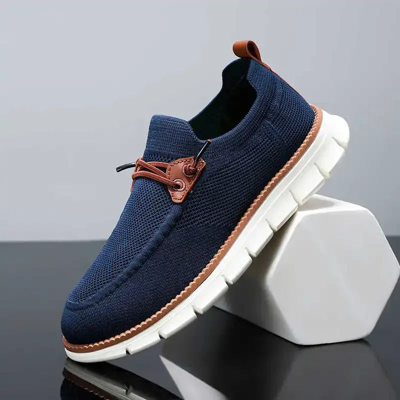 Navy blue slip-on shoe with brown accents on a gray background